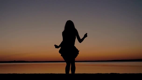 Silueta de una mujer bailando sexy al atardecer por el mar — Vídeo de stock