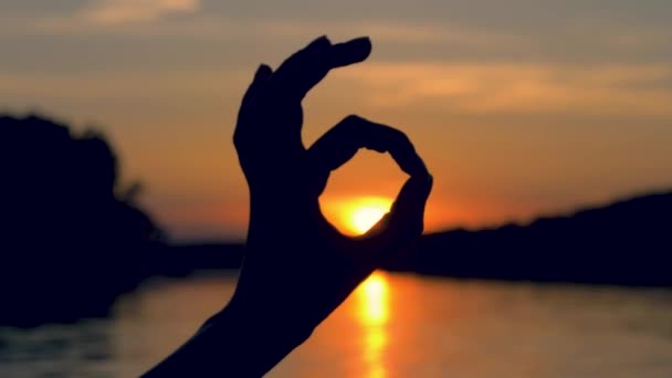 Närbild av Hand siluett visar Ok gesten i solstrålarna vid solnedgången — Stockvideo
