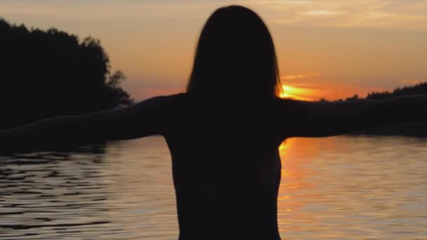 Mujer feliz al atardecer en el lago levantando sus brazos y dando la vuelta — Vídeo de stock