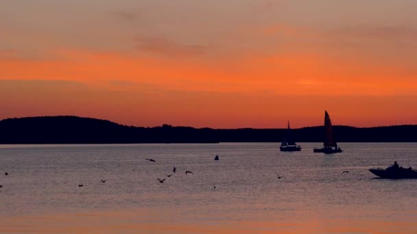 Вид на залив на закате, где плывут лодки или катаются на тюбингах — стоковое видео