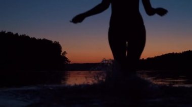 Kadın göl su ile çalışan gün batımını kollarını yukarı yükseltir karşılamak için