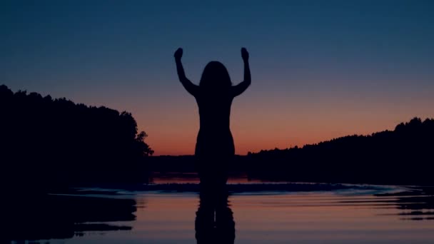 Σιλουέτα της γυναίκας σημαίνει γόνατο βαθιά μέσα στη λίμνη στο ηλιοβασίλεμα και πιτσιλιές νερού — Αρχείο Βίντεο