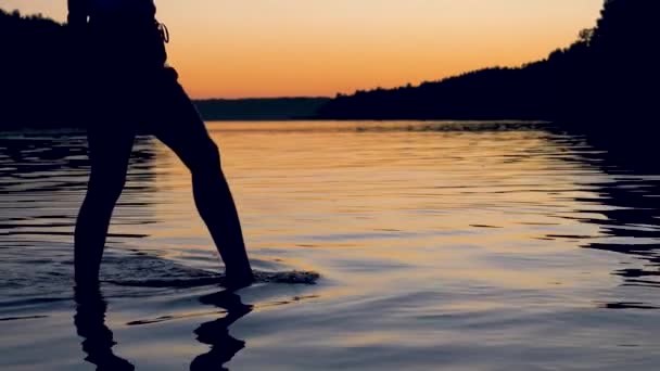 Las mujeres piernas elegantemente y con gracia va hasta la rodilla en el lago al atardecer escarlata — Vídeo de stock