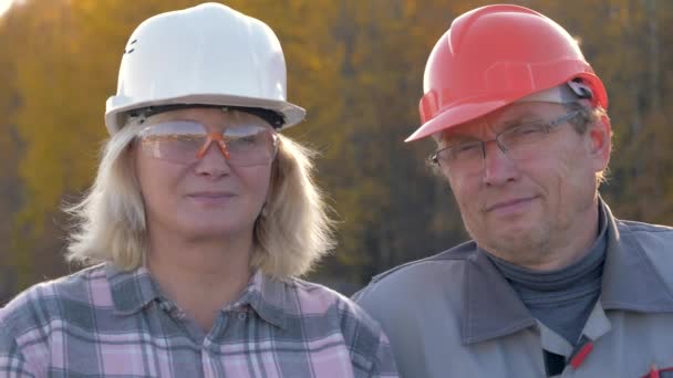 İnşaat işçileri bir erkek ve bir kadın kameraya bakarak bir kask içinde portresi — Stok video
