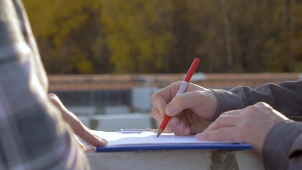 İnşaatçılar beraberlik elinde bir kalem İnşaat planı üzerinde yakın çekim — Stok video