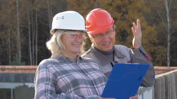 Ingenieros de mujeres y hombres en el sitio de construcción se divierten discutiendo el proyecto — Vídeo de stock