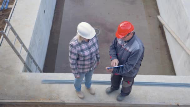 Vista superior del sitio de construcción donde el cliente y el constructor discuten el plan — Vídeo de stock