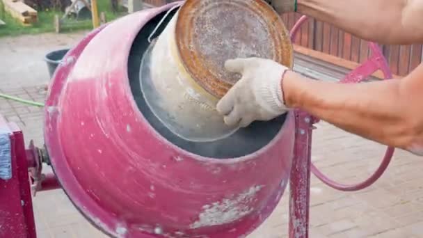 Nahaufnahme von Bauarbeiter schüttet Eimer mit Schotter und Zement in Betonmischer — Stockvideo