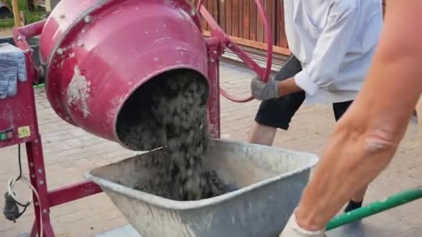 Betonmischer gießt fertige Lösung auf Baustelle in die Schubkarre — Stockvideo