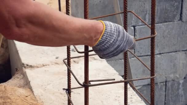 Hände Bauarbeiter in schmutzigen Handschuhen gebunden Stahldraht auf Bewehrungswerkzeug auf der Baustelle — Stockvideo