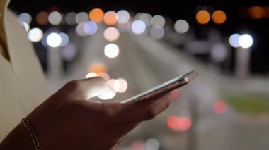 Görünümü yan, adam elinde bir akıllı telefon, mesaj kullanarak kapatmak, ekran kaydırma app. şehir gece, bulanık ışıkları arabalar ve aydınlatma touch