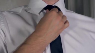 Beyaz adam ellerini beyaz bir gömlek üzerinde siyah kravat düzeltildi