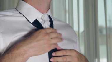 Beyaz adam ellerini beyaz bir gömlek üzerinde siyah kravat düzeltildi