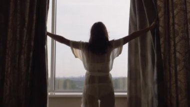 Bir güneşli sabah mutlu kadın perdeler pencere kenarındaki evde açar