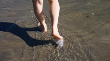 Ayakları suda ıslatın ve siyah kum sahilde yürüyüş bir hasta ve yaşlı beyaz adamın varisli damarlar ile