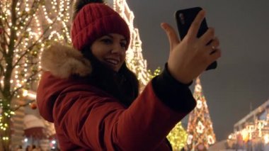 Kadın selfie Noel Fuarı'nda akşam ayakta Smartphone Taking