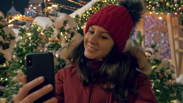 Gelukkige vrouw die Selfie op Smartphone achtergrond van versierde kerstbomen — Stockvideo