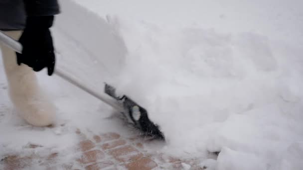 Крупним планом людина використовує лопату для чищення снігових тротуарів після снігопаду — стокове відео