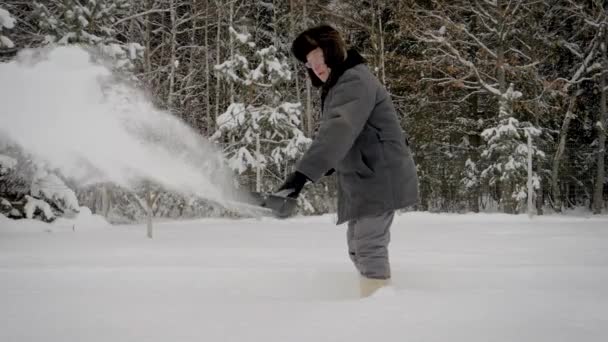 Férfi téli havazás lapát tisztítja a hó, a háttér, erdő út után — Stock videók