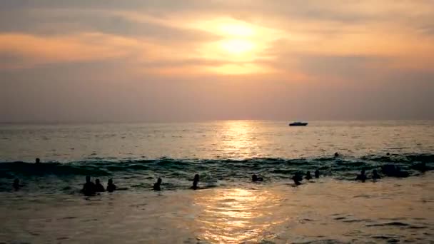 Mucha gente se balancea sobre las grandes olas junto al mar al atardecer — Vídeos de Stock