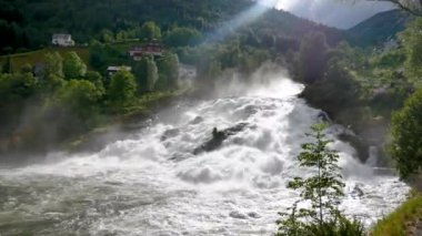 Hills yeşil çim ile şelale akar ve güneş ışını Rapids aydınlatır