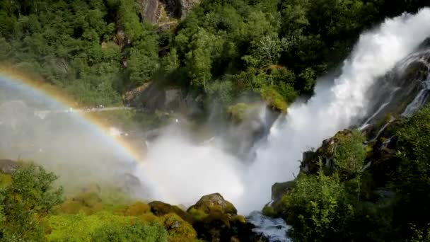 Cachoeira poderosa com rápida poeira de água no ar faz um arco-íris do sol — Vídeo de Stock