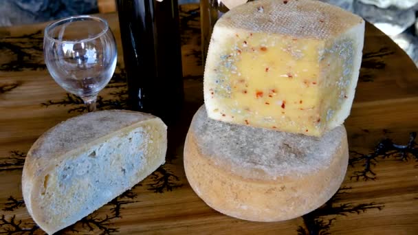 Отрежь кусочек сыра плесенью с бутылкой красного вина и бокалом на столе — стоковое видео