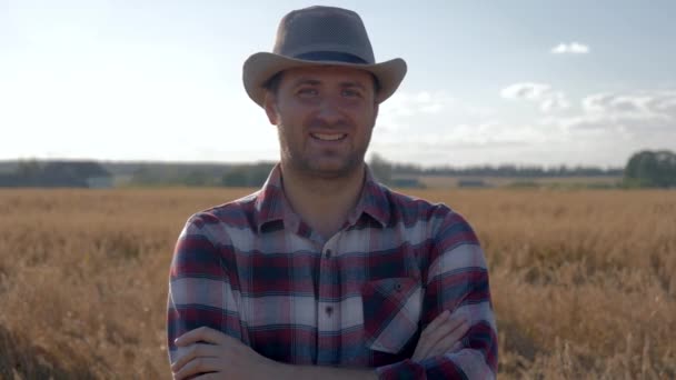 Retrato de un hombre agricultor parado en un campo de trigo en un soleado día de verano — Vídeo de stock