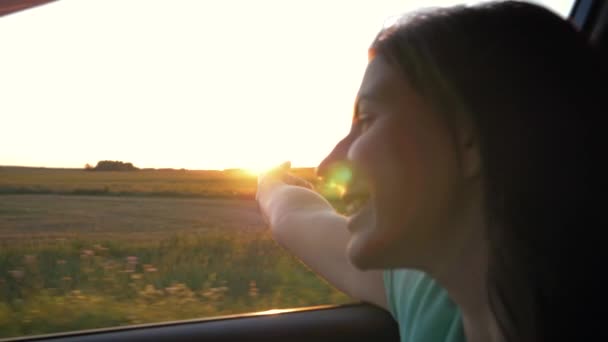 Mulher branca muito jovem no carro e mão jogando no ar ao pôr-do-sol Raios — Vídeo de Stock