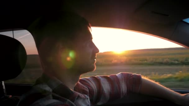 Hombre conducir en el coche en el fondo de la puesta del sol — Vídeos de Stock