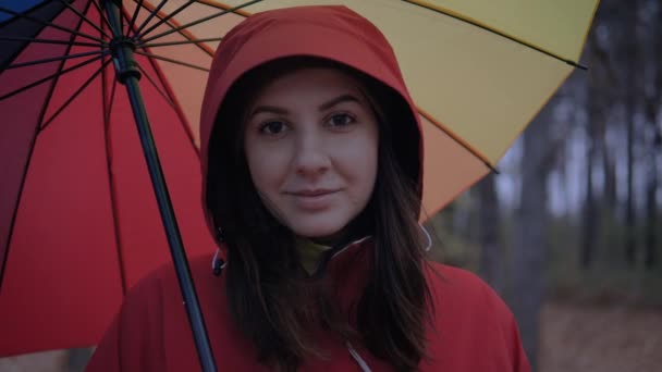 Porträt einer kaukasischen Frau mit Kapuze und Regenschirm im Herbst auf der Straße — Stockvideo