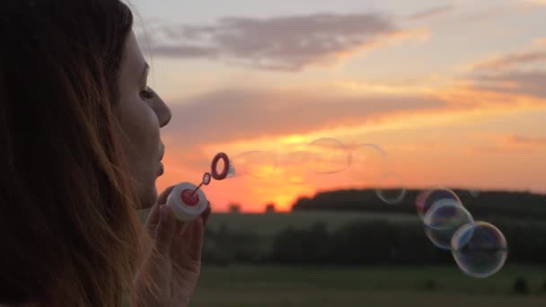 Joyeux jeune femme souffler des bulles au coucher du soleil sur la rue — Video