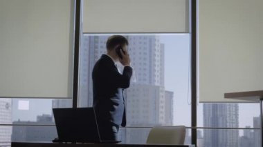 Ofis Penceresinde Telefonla Konuşan İşadamı Sonra İşyerine Oturur
