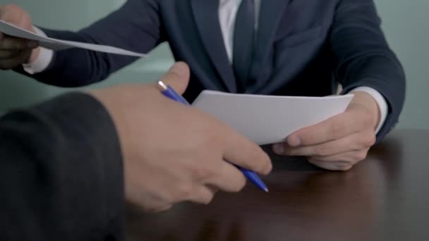 业务合作伙伴在文档上签名，通过握手密封交易 — 图库视频影像