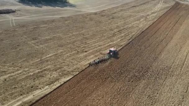 Landbouw trekker met ploeg ploegen het veld voor het planten van de luchtfoto — Stockvideo