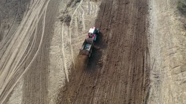 Traktor rider genom jordbruksmark och gödsling den med gödsel — Stockvideo