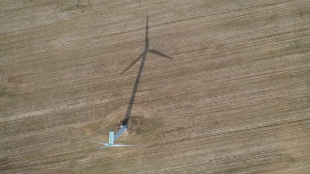 Blick von oben auf eine funktionierende Windkraftanlage und ihren Schatten auf dem Feld — Stockvideo