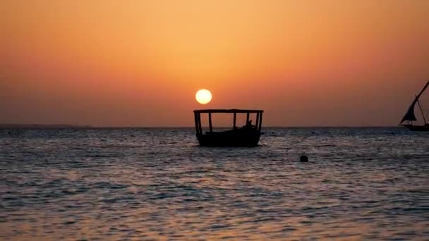 Západ slunce na tropickém oceánu s velkým červeným sluncem a siluetou rybářských člunů — Stock video