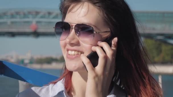 Jonge aantrekkelijke blanke vrouw in zonnebrillen met plezier praten op telefoon — Stockvideo