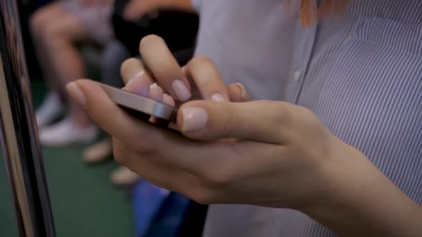 Gros plan de mains de femme utilisant un smartphone debout dans une voiture de métro — Video