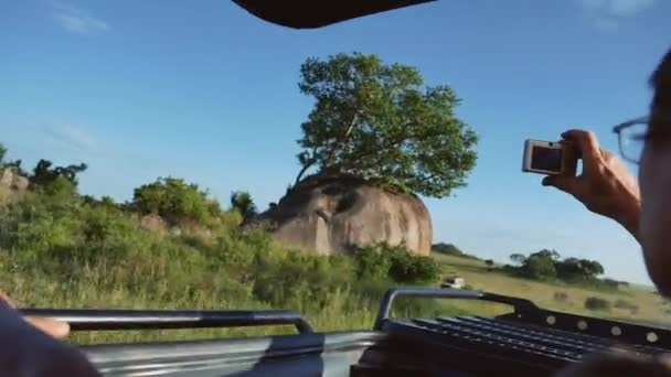 男子驾驶野生动物园吉普车在非洲平原的哈奇在屋顶汽车拍照 — 图库视频影像