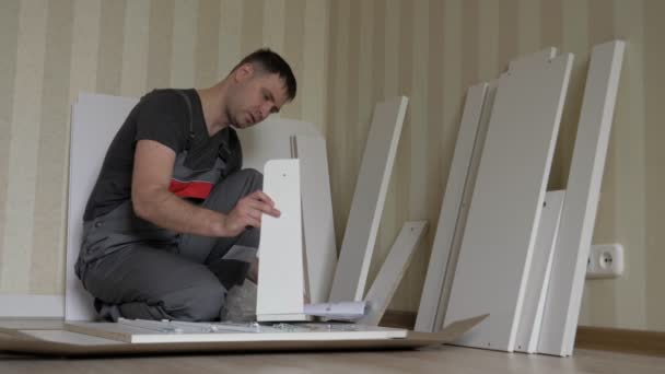 Сборка мебели для рабочих читает инструкции и проверяет детали — стоковое видео