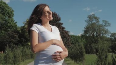 Güneşli bir yaz gününde dışarıda sıcaklık ve güneşin tadını çıkaran hamile kadın