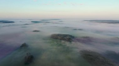Gün doğumunda yoğun sisle kaplı kırsal bir alanın üzerinde uçan hava.