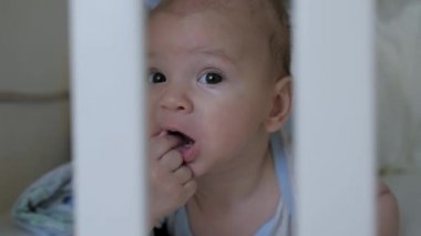 Beşikte yatarken parmağını emen sevimli bir çocuğun yakın portresi.