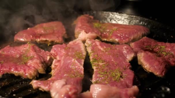 Κοντινό πλάνο της μαγειρικής μπριζόλες ωμό κρέας σε ένα τηγάνι σχάρα — Αρχείο Βίντεο