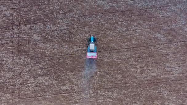 トレーラーでトラクターの上を飛行する航空機は、農村部のフィールドに肥料を噴霧します — ストック動画