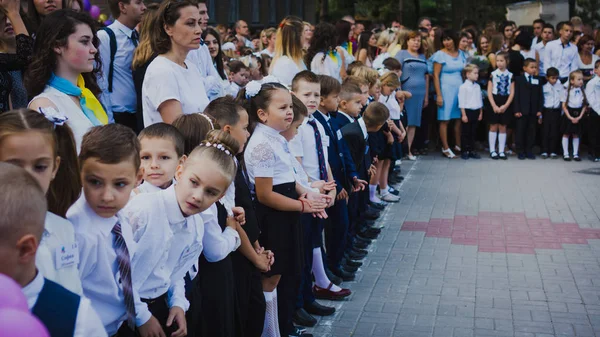 Zaporozhye, Ucraina - 1 settembre 2018: i primi alunni stanno su un righello all'aria aperta con insegnanti e studenti delle scuole superiori sulla linea della scuola cerimoniale il giorno della conoscenza — Foto Stock