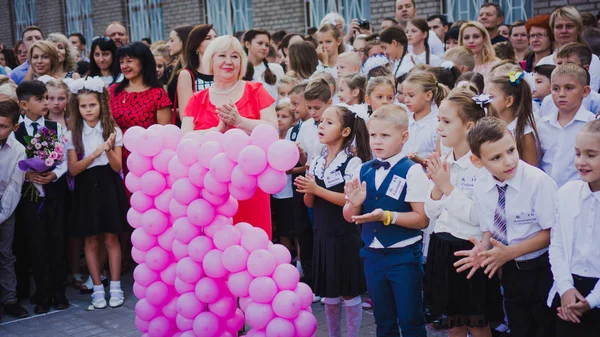 Zaporozhye, Ukraine - 1. September 2018: Erstklässler stehen am Tag des Wissens mit Lehrern und Gymnasiasten auf einem Lineal im Freien an der feierlichen Schullinie. — Stockfoto