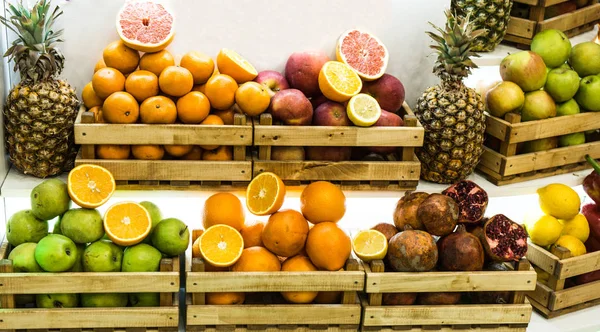 Boxes with different kinds of fresh fruits displayed in wooden crates at the grocery store.